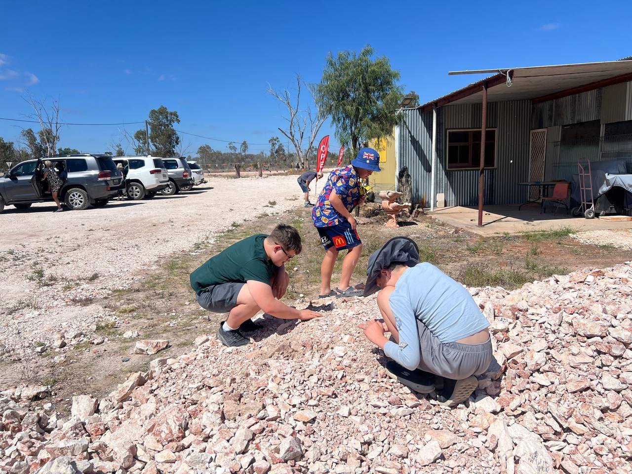 Kids crouched on a pile of pinkish-white mullock, sifting through the rocks in the sun