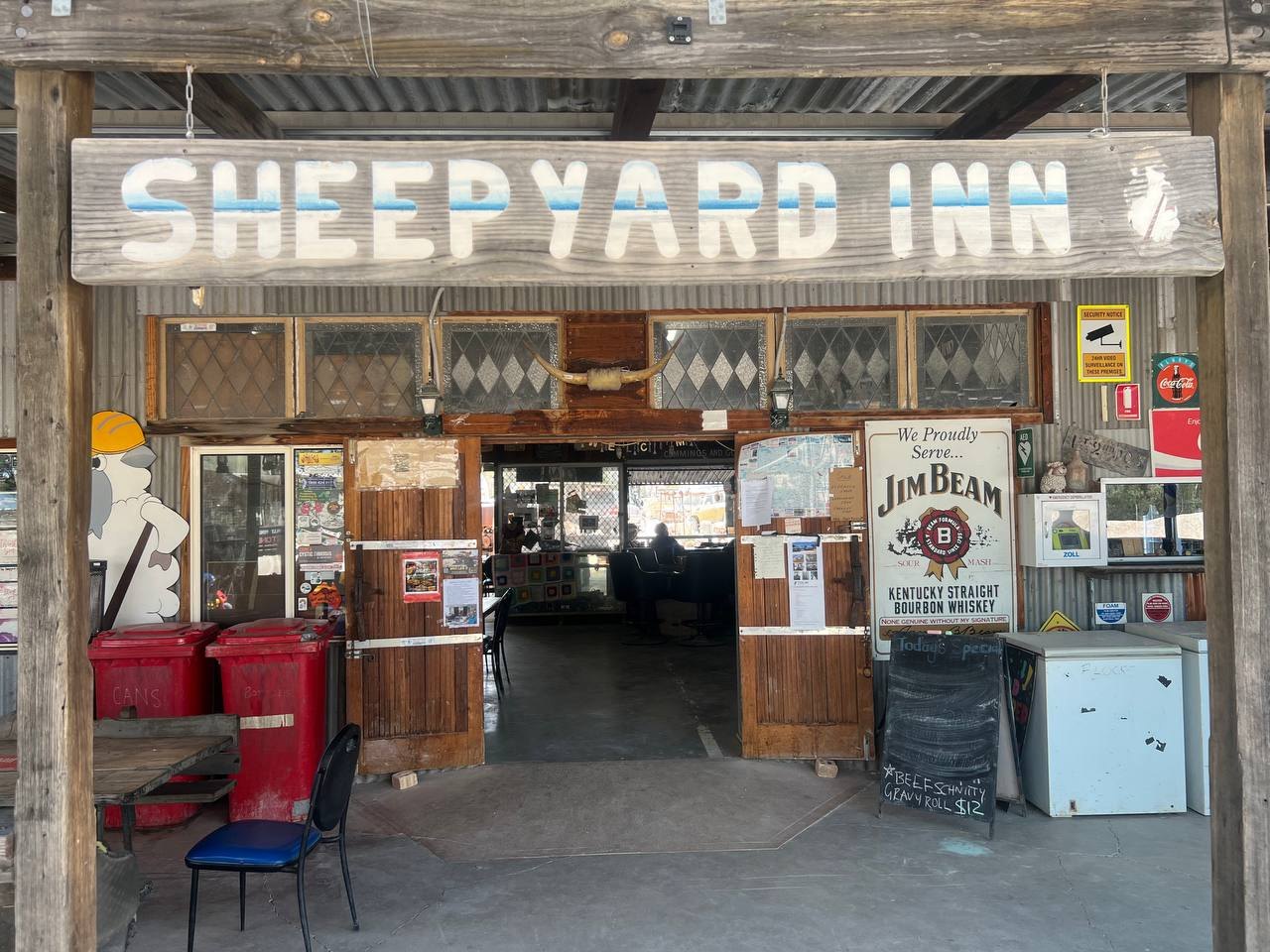 The front veranda of the Sheepyard Inn, with its hanging sign, longhorn skull, and open doors into the bar