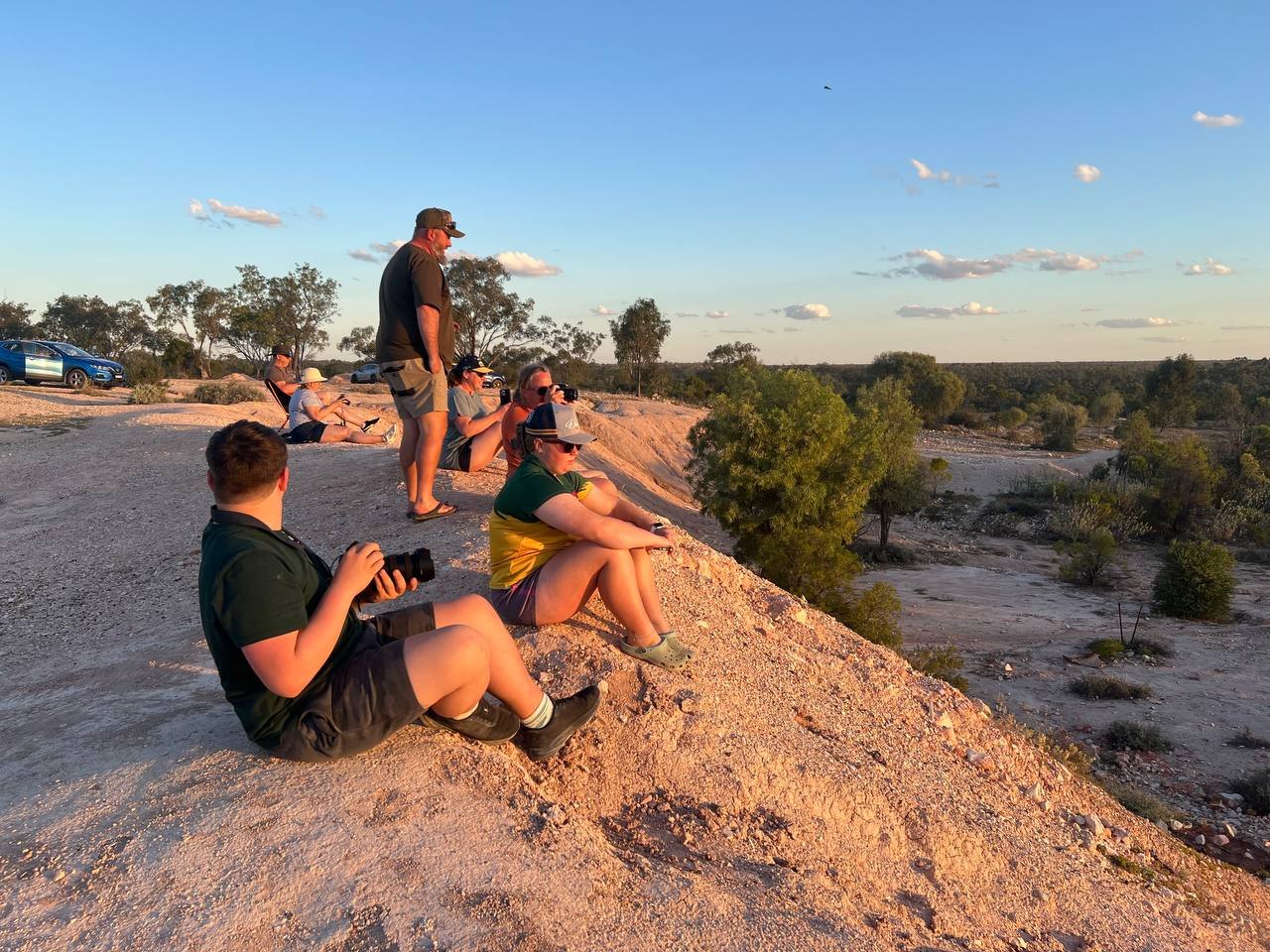 The group on the rocky hilltop at golden hour, watching and photographing the sunset